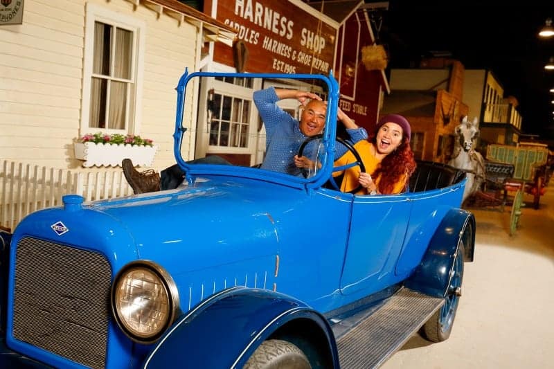 Two people pose inside the blue McLaughlin car