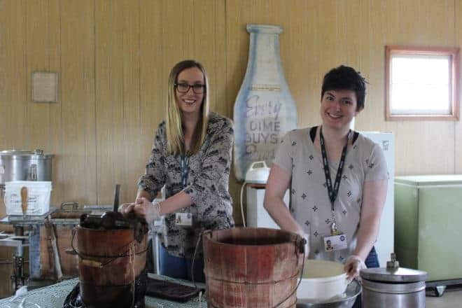 two young women make ice cream using hand-cranked freezers in the Dairy Building at WDM North Battleford