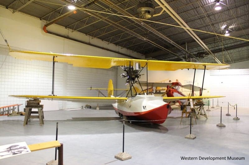 Replica flying boat with yellow wings and white and red body sitting on the floor at the WDM Moose Jaw