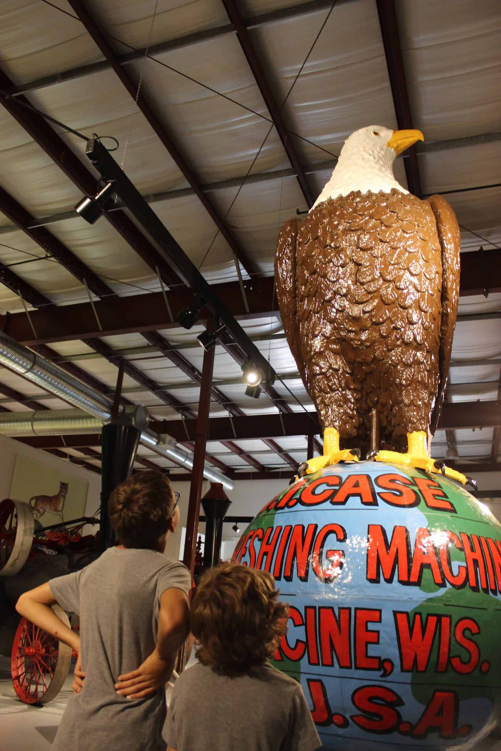 Two young boys looking up at the Case Eagle as it sits on a large globe.