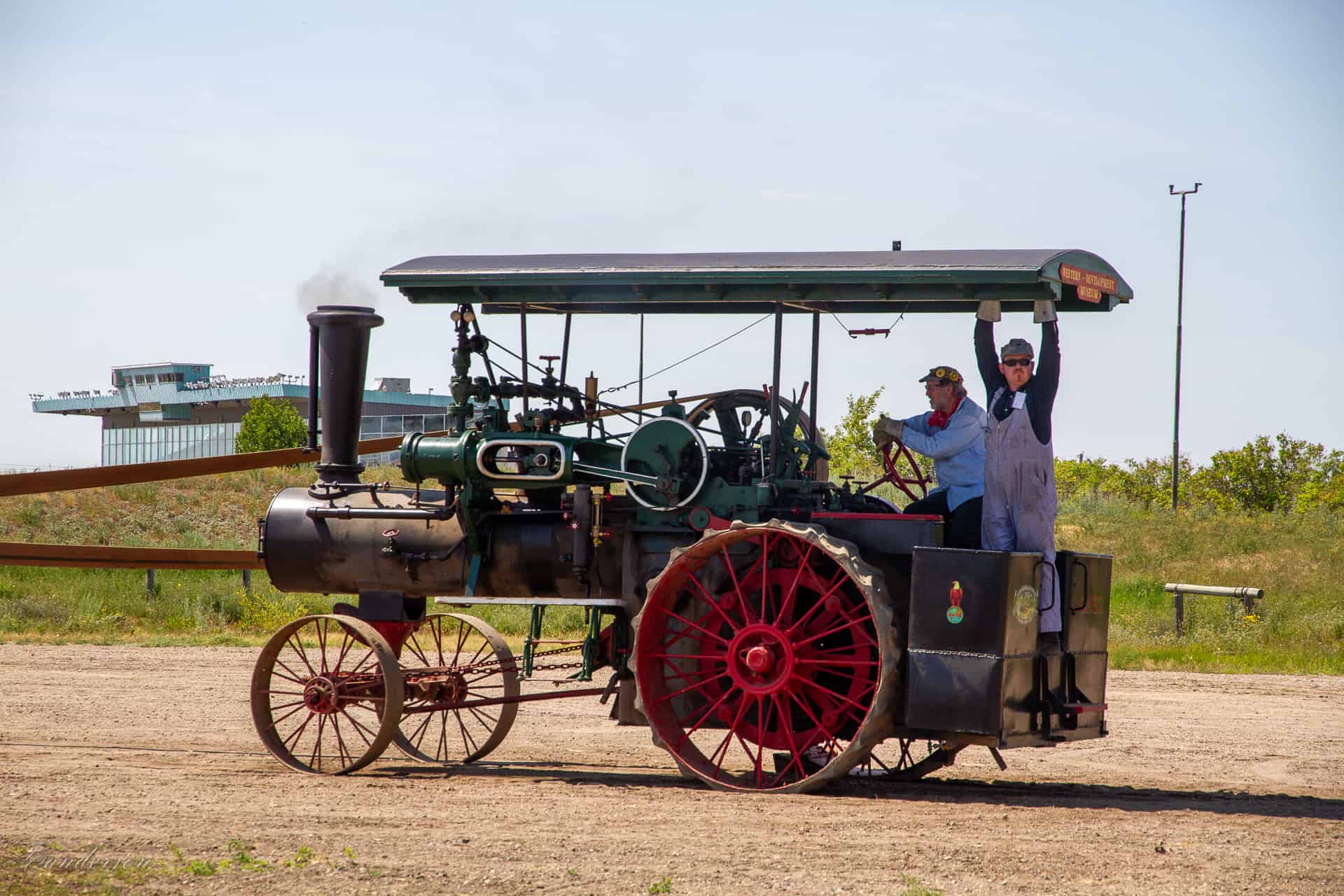 Two men running a steam traction engine out on a sunny day.