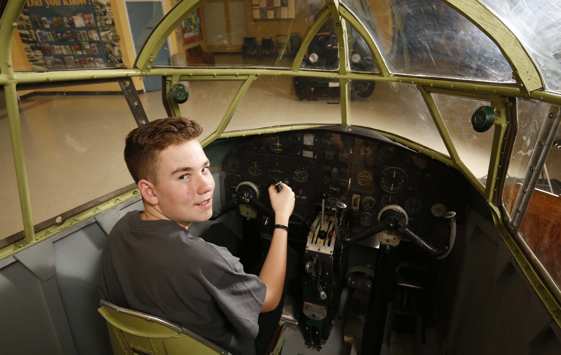 Young man sits in the cockpit of an Airspeed Oxford Mark I and looks out