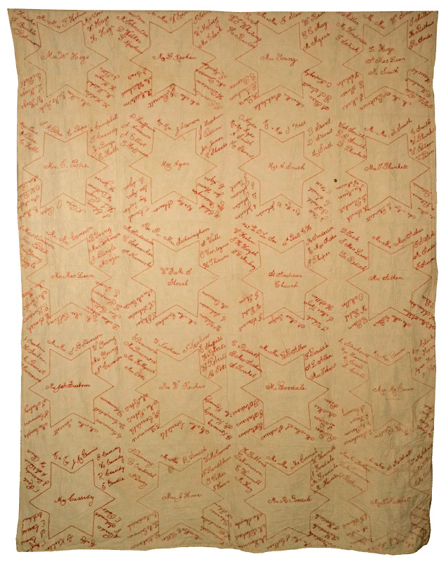 Quilt with names embroidered in red thread.